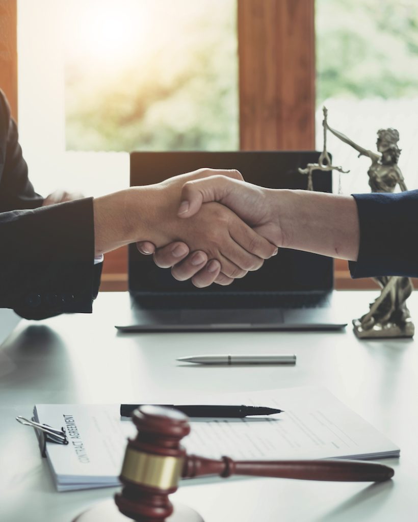 Businessman shaking hands to seal a deal with his partner lawyers or attorneys discussing a contract agreement..